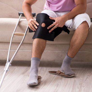 Man with a leg injury, putting on a brace.