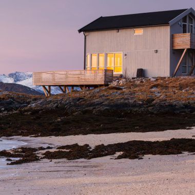 A small house in Norway standing by a lake in the evening.