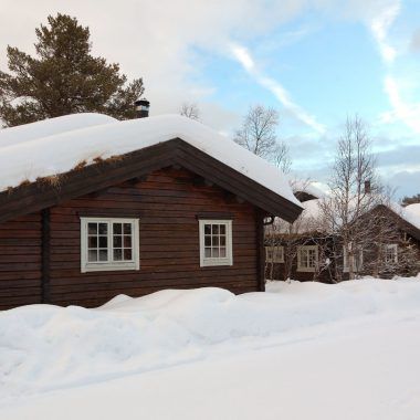 A snow-covered, wooden Norwegian cottage.